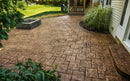Brown stamped concrete patio with a rectangular stone pattern beside a landscaped garden