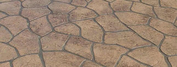 Tan and brown Bushrock concrete overlay with irregular textured rock shapes separated by dark gray joints.