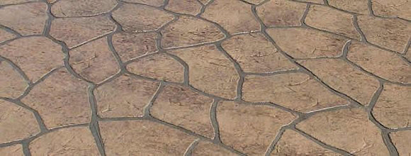 Tan and brown Bushrock concrete overlay with irregular textured rock shapes separated by dark gray joints.