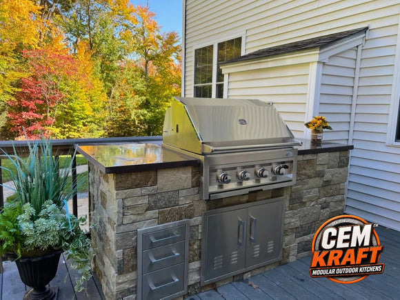 CEM Kraft stone-look outdoor kitchen on a deck with dark countertop, built-in grill, double access doors, and drawers