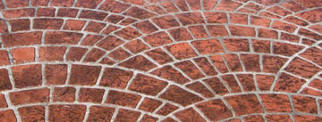 Reddish-brown Cobble Fan concrete overlay with overlapping curved cobblestone patterns and light gray joint lines