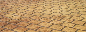 Tan cobble stone pattern concrete overlay with rounded rectangular stone shapes in staggered rows and dark joint lines