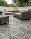 Gray wood-plank stamped concrete patio with visible grain, outdoor seating, and a circular fire pit